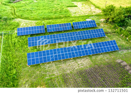 Blue solar photo voltaic panels mounted on metal frame standing on ground with green grass in field. Blue solar photo voltaic panels mounted on metal frame standing on ground with green grass in field. 132711501