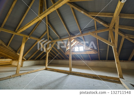 Attic of a building with wooden beams of a roof structure and a small window. Attic of a building with wooden beams of a roof structure and a small window. 132711548