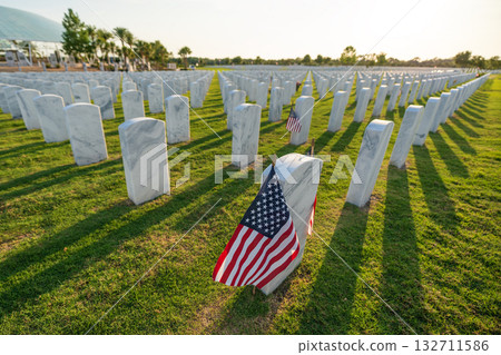 American army national cemetery with rows of white headstones and USA flag on green grass lawn. Memorial Day concept 132711586