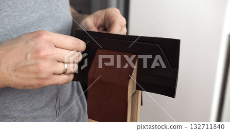 Artisan sewing handmade leather wallet by hand with strong needle Artisan sewing handmade leather wallet by hand with strong needle 132711840