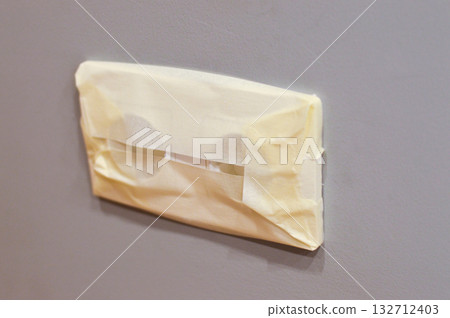 The outlet with sticky tape to protect it from paint during repairs. 132712403