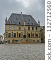 Osnabruk historic Town Hall features a slate roof, towers, stone statues, and central stairs leading to the entrance, set on a cobbled square. 132712560