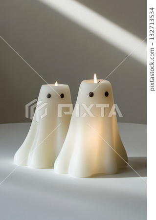 Ghost-shaped candles glowing softly on a table creating a cozy Halloween atmosphere 132713534