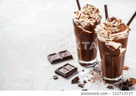 Two chocolate drinks with whipped cream and chocolate chips on a table 132713537