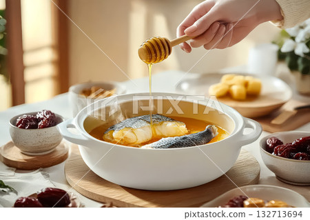 Person is pouring honey into a pot of food Person is pouring honey into a pot of food 132713694