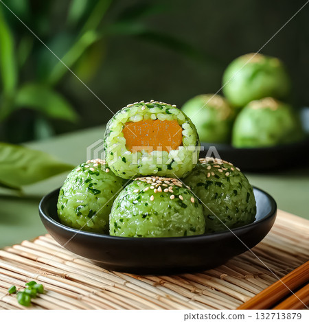 Bowl of green rice balls with one of them cut in half Bowl of green rice balls with one of them cut in half 132713879