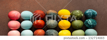 Brightly colored Easter eggs are arranged in a grid, displaying shades like pink, blue, green, and yellow. These eggs symbolize renewal and are often part of festive gatherings, banner 132714883