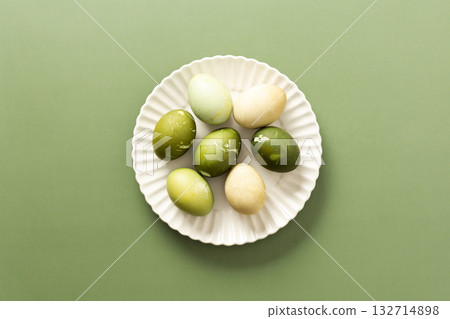 A collection of beautifully dyed Easter eggs in various shades of green and pale colors sits on a white plate, symbolizing joy and renewal during the spring season A collection of beautifully dyed Easter eggs in various shades of green and pale colors sits on a white plate, symbolizing joy and renewal during the spring season 132714898