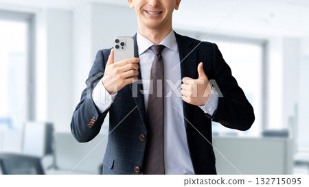 A man holding a smartphone and making a thumbs up pose A man holding a smartphone and making a thumbs up pose 132715095