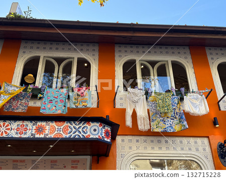 Patterned laundry drying in sunlight against orange wall. Playful decor, home culture and Mediterranean everyday life. Patterned laundry drying in sunlight against orange wall. Playful decor, home culture and Mediterranean everyday life. 132715228