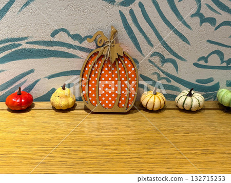 Mini pumpkins and wooden decor on shelf against painted wall. Autumn interior styling, seasonal decoration and warm visual mood. 132715253