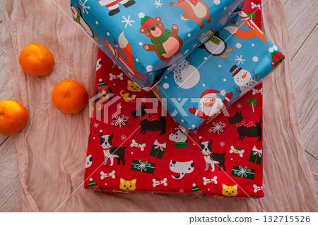 Two wrapped Christmas gift boxes paired with fresh tangerines, creating a cheerful festive composition. Perfect for holiday, Christmas, and winter-themed projects. 132715526