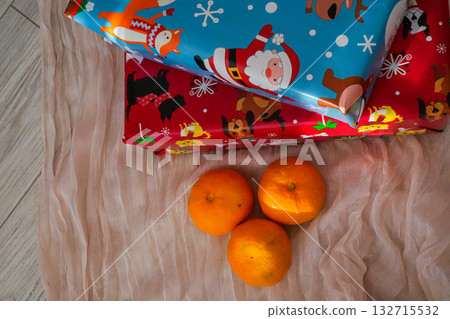 Two wrapped Christmas gift boxes accompanied by fresh tangerines. Festive holiday composition with seasonal colors, perfect for Christmas, New Year, and winter themes. 132715532