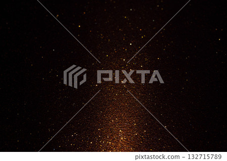 Dark brown micro grained surface with streak of light revealing soft golden shimmer in gentle shadow 132715789