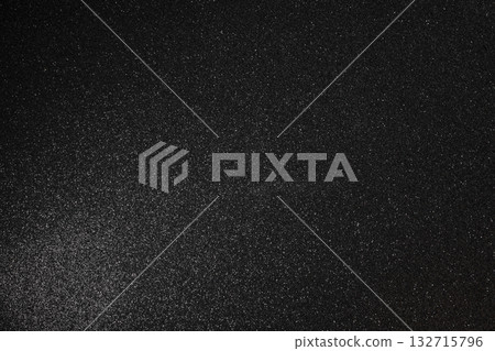 Sharp focused black glitter surface with fine grain soft glowing light and scattered bright sparkles 132715796