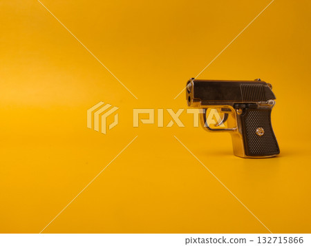 A small handgun is on a yellow background with copy and text space. 132715866