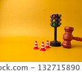 The image shows a miniature traffic light, small traffic cones, and a gavel. This combination of objects can be interpreted as a representation of traffic law and its enforcement. 132715890
