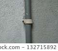 The image shows a PVC pipe with a pipe clip or saddle clamp. This type of clamp is used to secure the pipe to a wall or other surface. 132715892