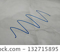 The image shows a blue, continuous, wavy line drawn on a piece of white paper. 132715895