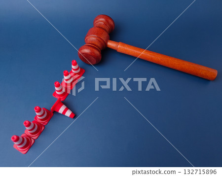 The combination of a gavel and traffic cones can symbolize legal obstacles or the law creating barriers. 132715896