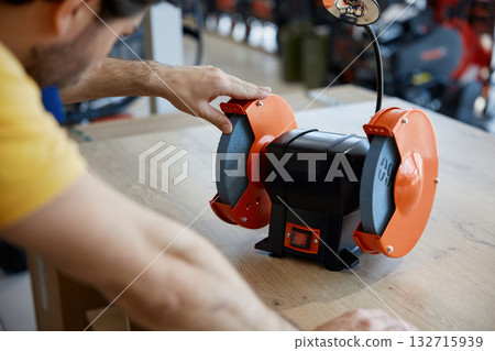 Young worker diligently working on a grinder Young worker diligently working on a grinder 132715939