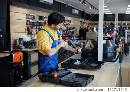 A man is working on a drill inside a retail store A man is working on a drill inside a retail store 132715943