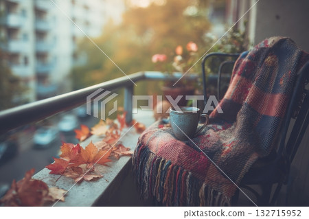 Balcony with chair blanket and tea cup overlooking autumn leaves with cozy atmosphere and warm light 132715952