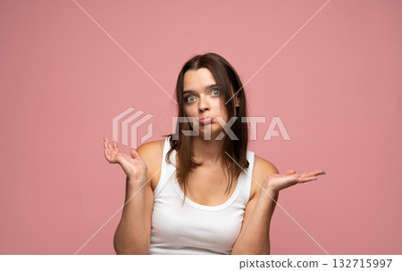 Confused young woman shrugging shoulders with questioning look on pink background Confused young woman shrugging shoulders with questioning look on pink background 132715997