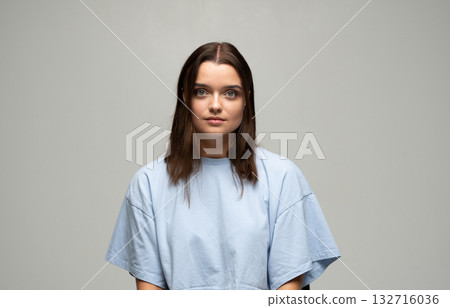Calm young woman looking at camera with neutral expression in studio portrait Calm young woman looking at camera with neutral expression in studio portrait 132716036