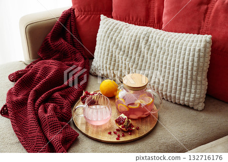 Glass Teapot and Teacup with Pomegranate Drink with Ginger and Citrus on Cozy Sofa with Autumn Decor Glass Teapot and Teacup with Pomegranate Drink with Ginger and Citrus on Cozy Sofa with Autumn Decor 132716176