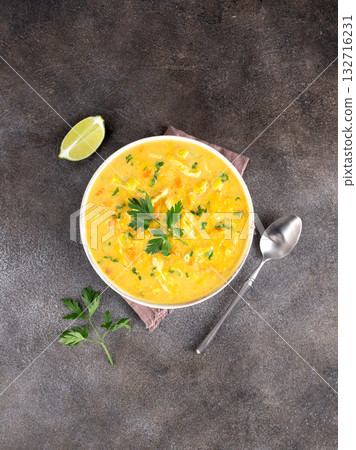 Top view of Mulligatawny soup with herbs and lime on rustic table. Traditional Indian food. 132716231