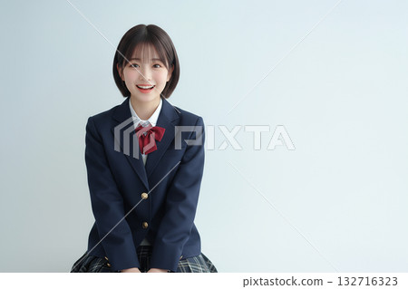 身穿校服的微笑女學生坐在那裡 132716323