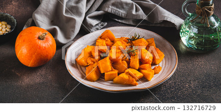 Pieces of baked pumpkin with rosemary on a plate on the table web banner Pieces of baked pumpkin with rosemary on a plate on the table web banner 132716729