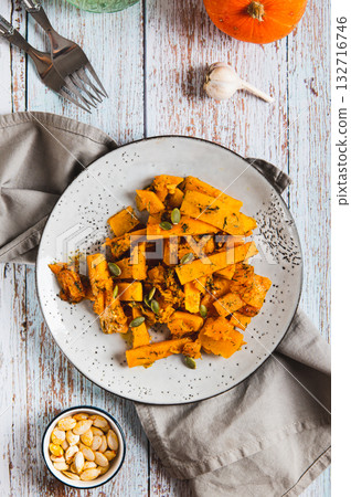 Roasted pumpkin slices with garlic and dill on a plate on the table top and vertical view 132716746