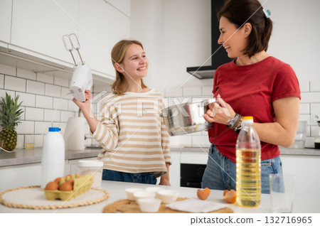 Happy Little Girl And Mother Baking And Having Fun Playing With A Mixer In The Kitchen 132716965