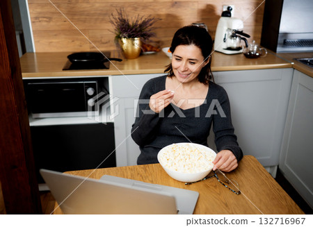 Smiling Girl Watching A Video On A Laptop Screen And Eating Popcorn 132716967