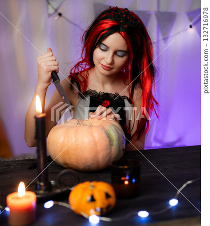 Cute Little Girl In A Halloween Witch Wig Carving A Halloween Pumpkin In A Decorated Room 132716978