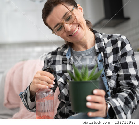 Girl Wetting Home Pot Plant At The Kitchen 132716983