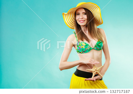 Woman in yellow hat holding white shell Woman in yellow hat holding white shell 132717187