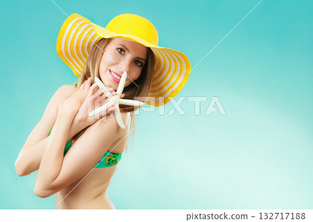 Woman in yellow hat holding white shell Woman in yellow hat holding white shell 132717188