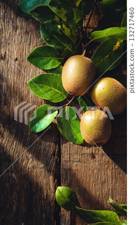 Fresh Sapotes Surrounded by Green Leaves on Rustic Wooden Table in Natural Light 132717460