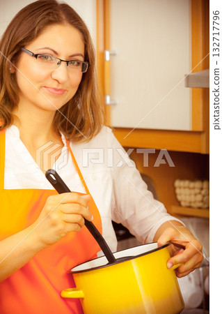 Woman with ladle and pot in kitchen Woman with ladle and pot in kitchen 132717796