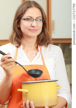 Woman with ladle and pot in kitchen Woman with ladle and pot in kitchen 132717799