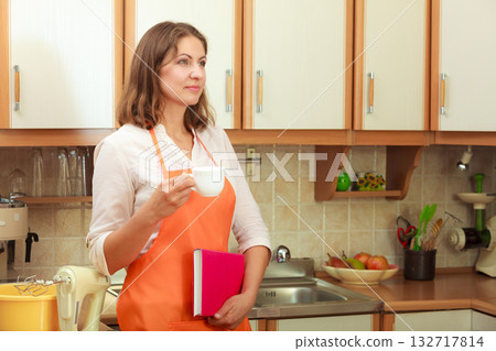 Female cook relaxing in kitchen. Female cook relaxing in kitchen. 132717814