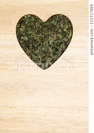 Dried nettle leaves heart shaped on wooden surface Dried nettle leaves heart shaped on wooden surface 132717869