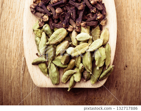 cardamom pods and cloves on wooden spoon 132717886