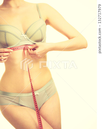 Woman in bra lingerie measuring her chest breasts. 132717979