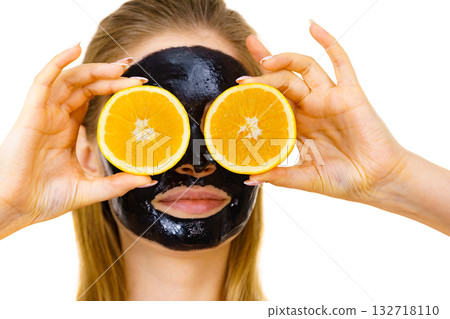 Girl black carbo mask on face holds orange fruit Girl black carbo mask on face holds orange fruit 132718110