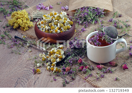 medicinal herbs. fresh thyme flowers, dried chamomile and immortelle flowers on a wooden table. cup of thyme tea and various herbs 132719349