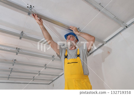 Senior adult worker fixing aluminum batten for gypsum ceiling Senior adult worker fixing aluminum batten for gypsum ceiling 132719358